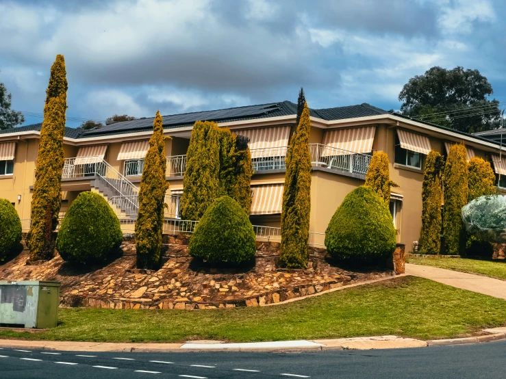 a small, four story apartment complex with landscaping and a sculpture in front of it