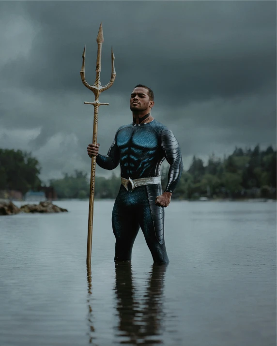 a man in a body suit and sword standing in water