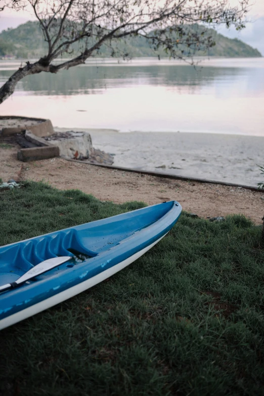 an empty kayak sitting on the shore near the water