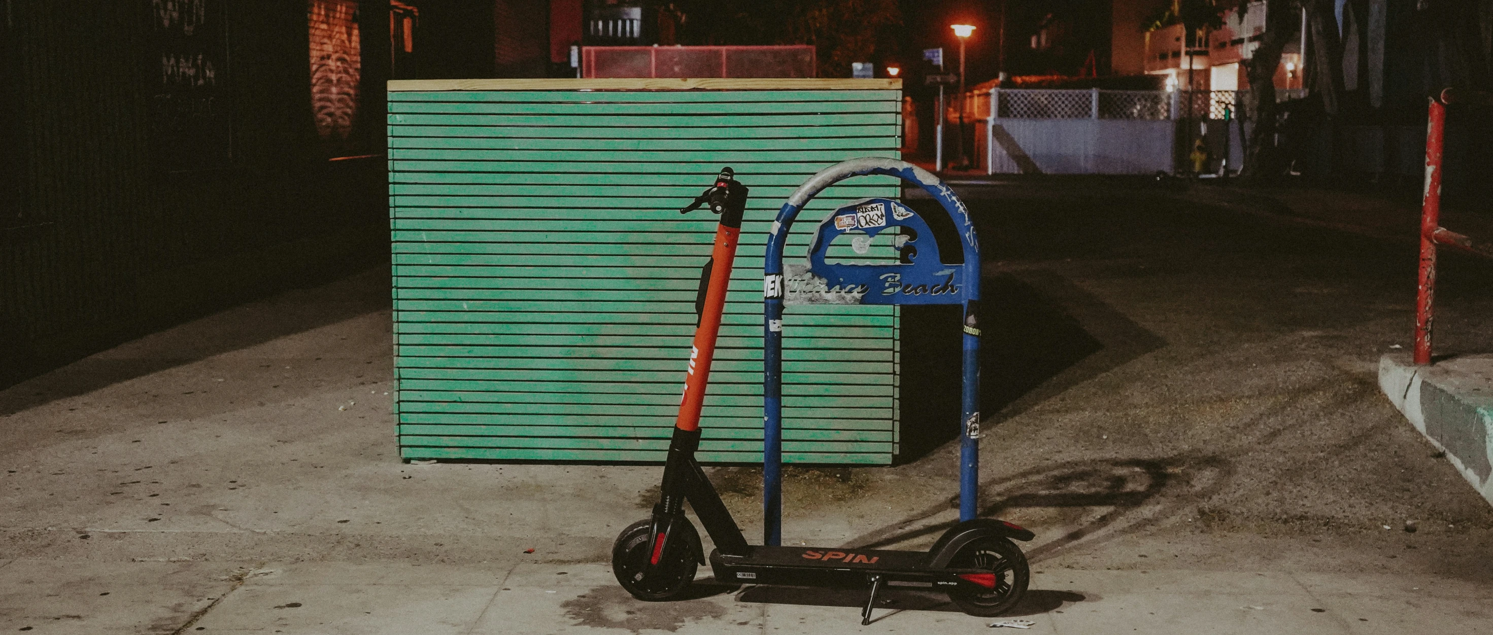 a scooter parked on the sidewalk near a green gate