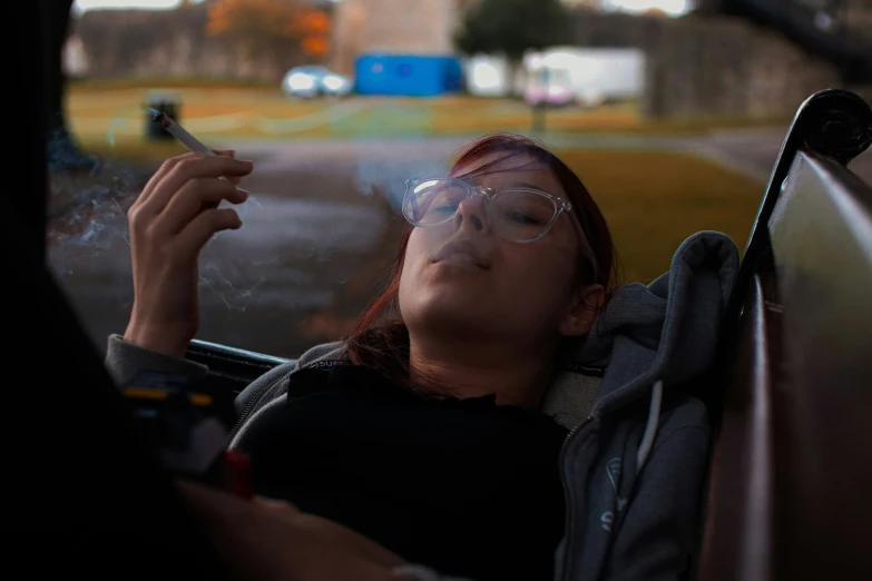 a woman smoking a cigarette in the back seat of a car