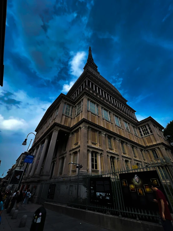 a tall building with a very steeple near a gate