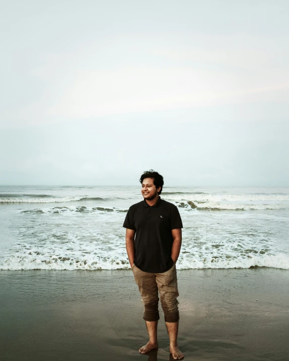 a man standing in the sand of a beach near the water