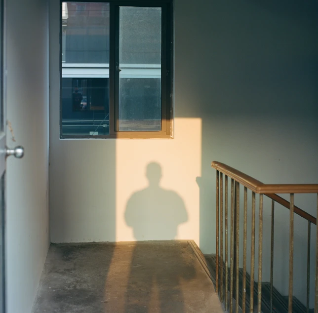 the shadow of a man is cast on a wall next to an open window