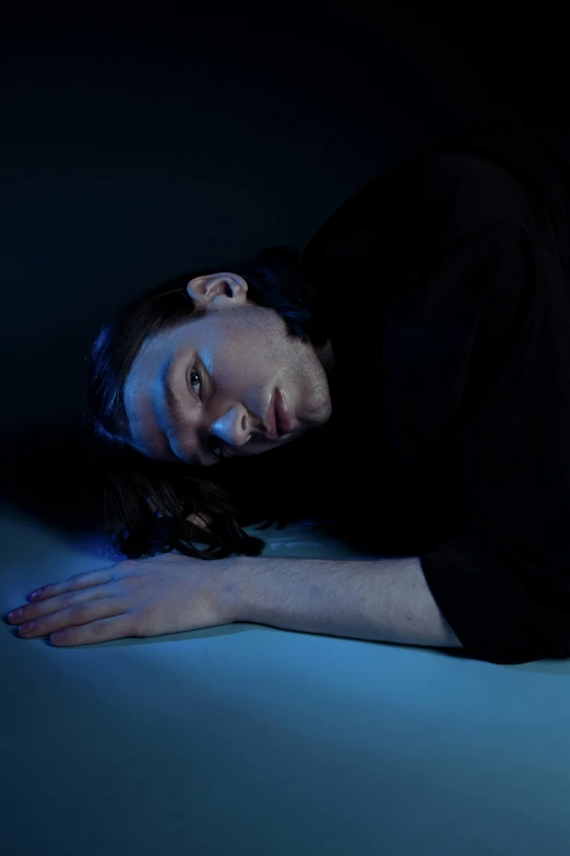 a person with long hair laying down on the ground