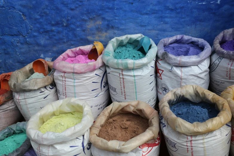 many bags of different colored powder on top of each other