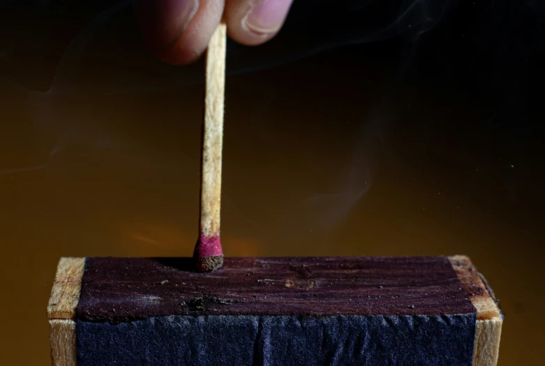 a hand holding a cigarette and a match in it