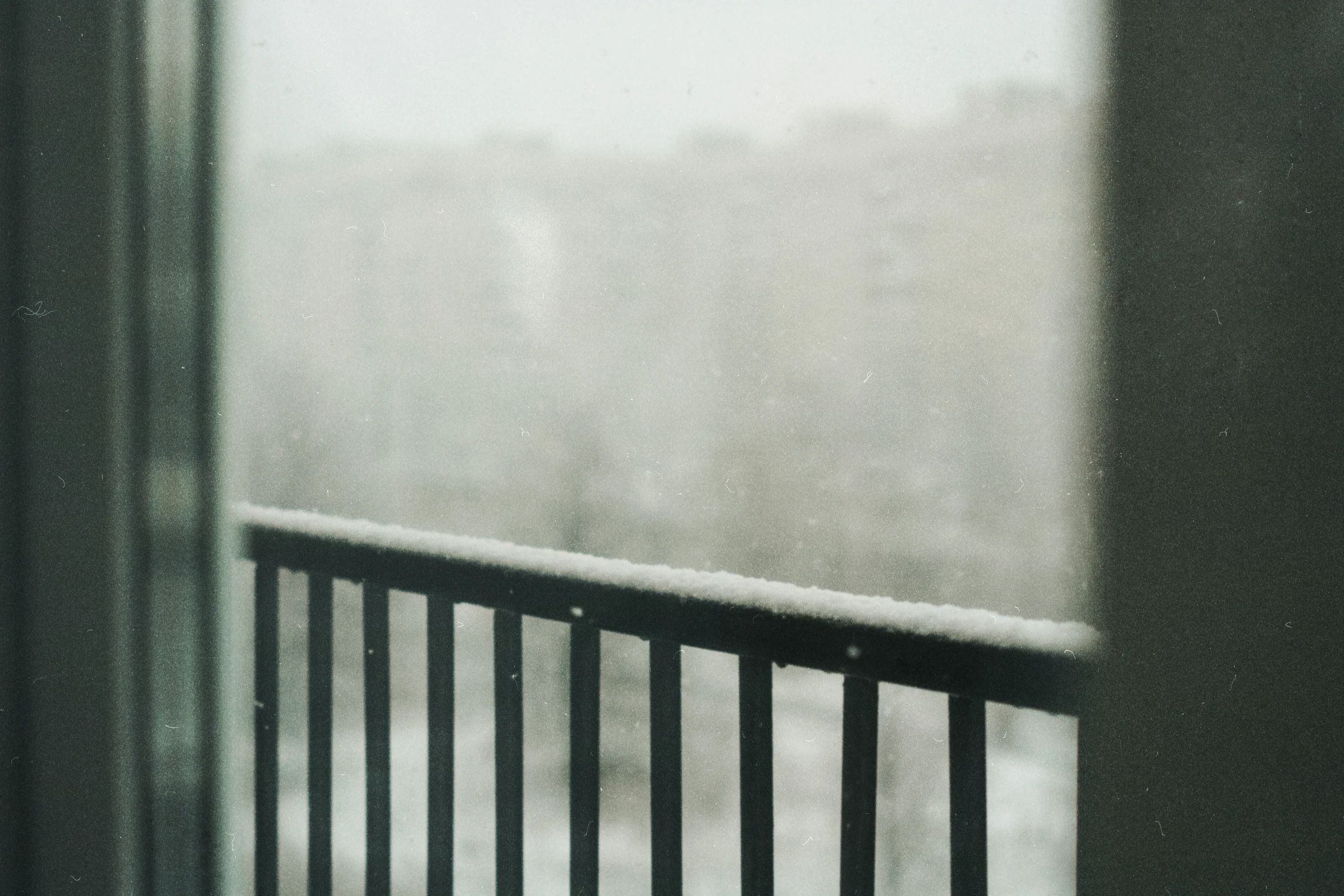 the view from inside of a window with the snow covered balcony