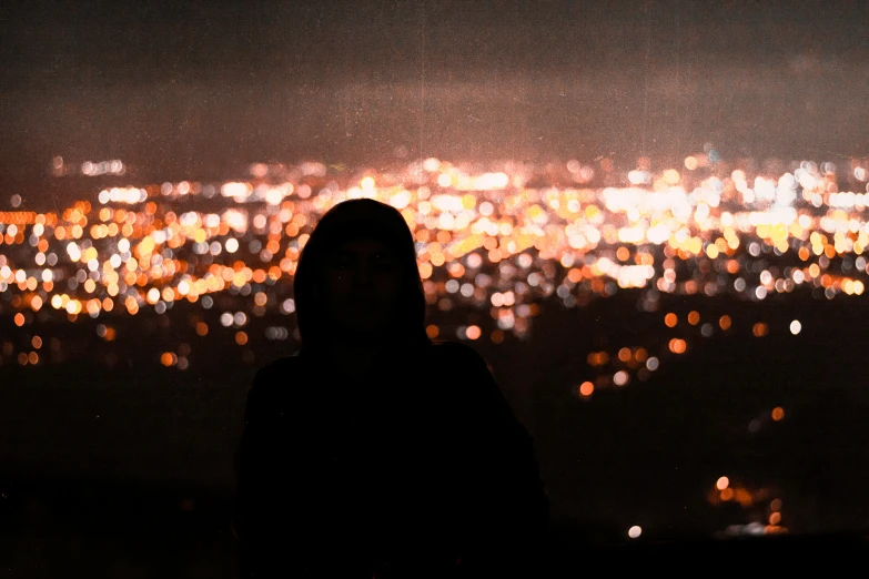 woman in dark, with large city lights in the distance