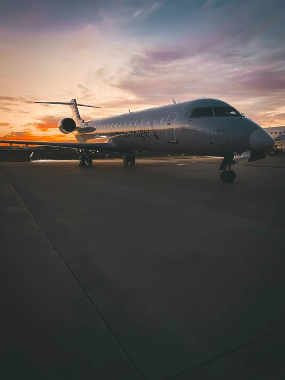 an airplane on the runway with a bright sun setting in the background