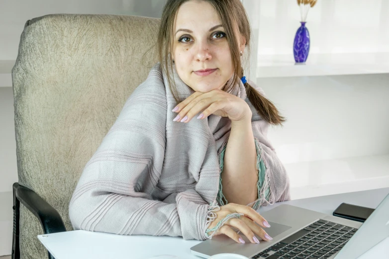 a woman sitting at a desk with a laptop and pen