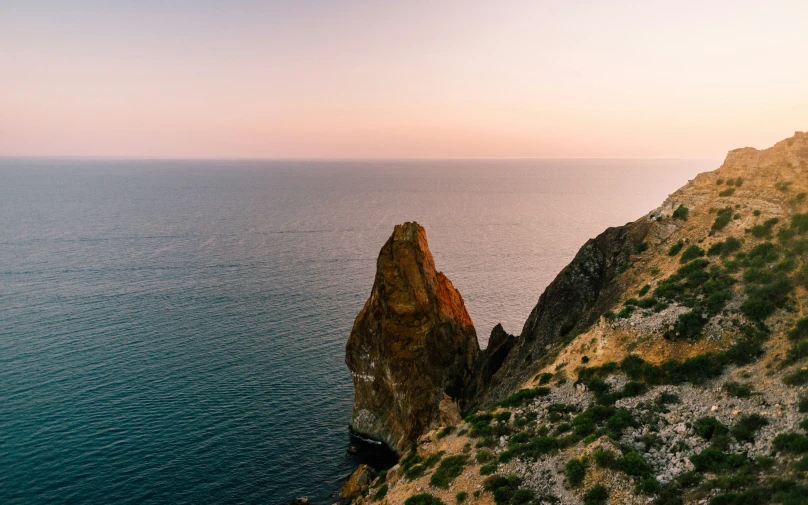 a long stone cliff on the ocean with water