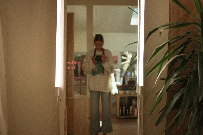 a woman in white shirt standing by large mirror