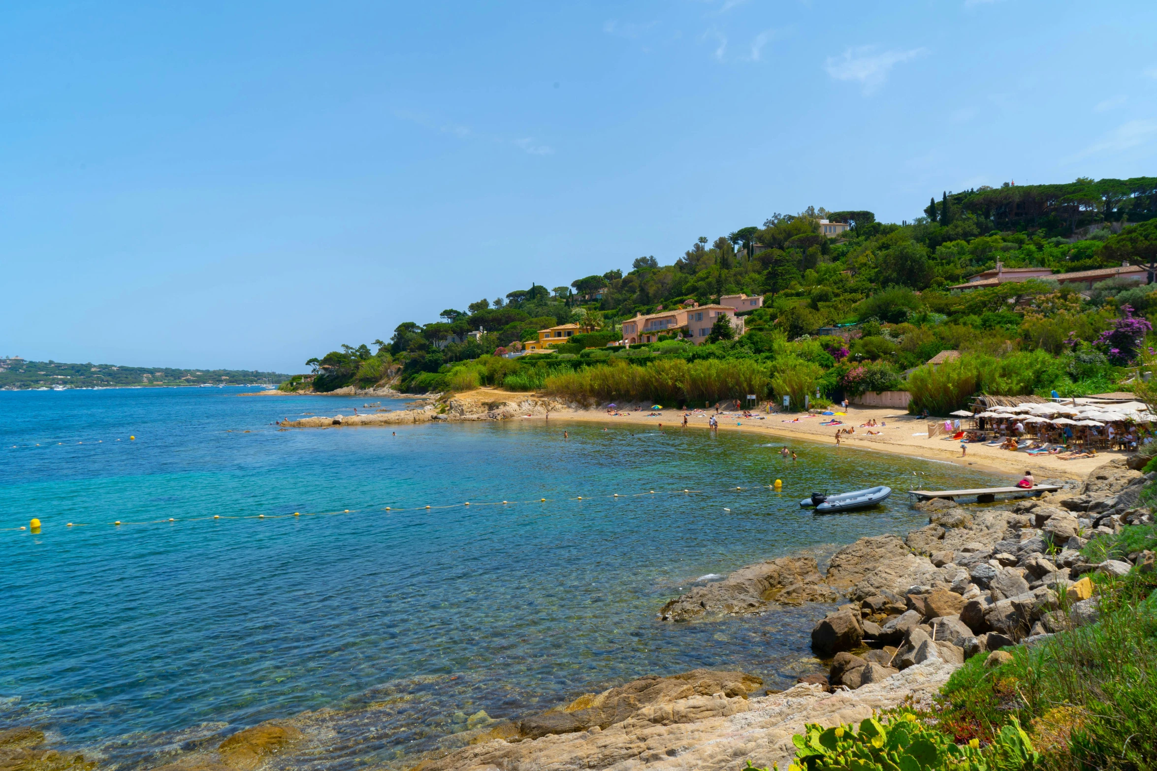 people are swimming in clear blue water beside the beach