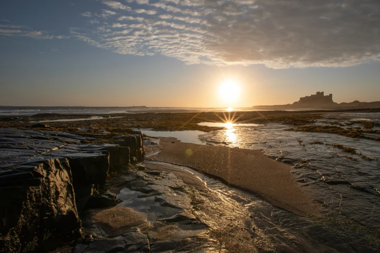 a beach with sun reflecting off the ocean water