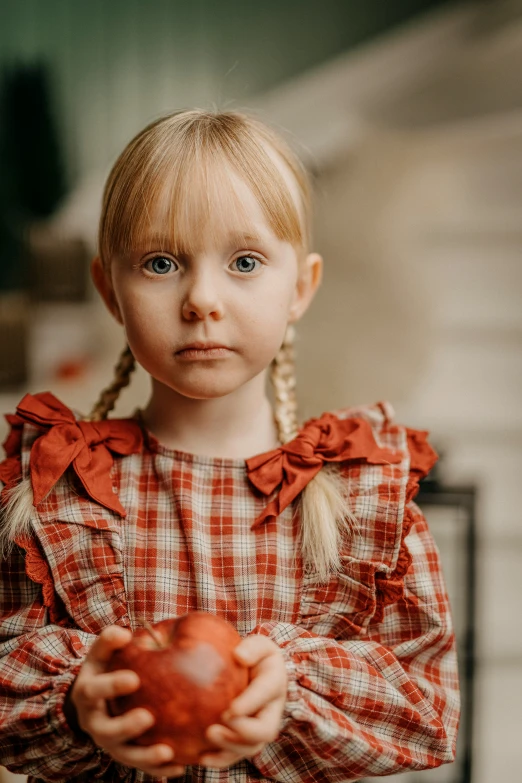  with pigtails and red checkered dress holding apple