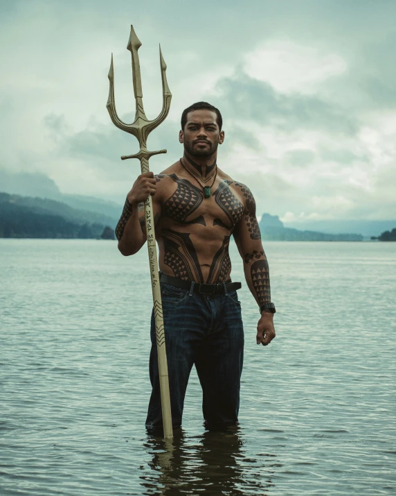 man standing in water holding an odd looking stick