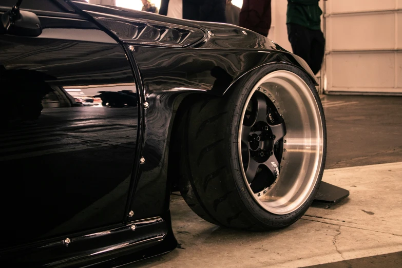 the front wheel of a black car with silver rims