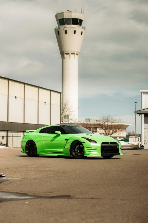 a bright green car sitting in front of an airport control tower