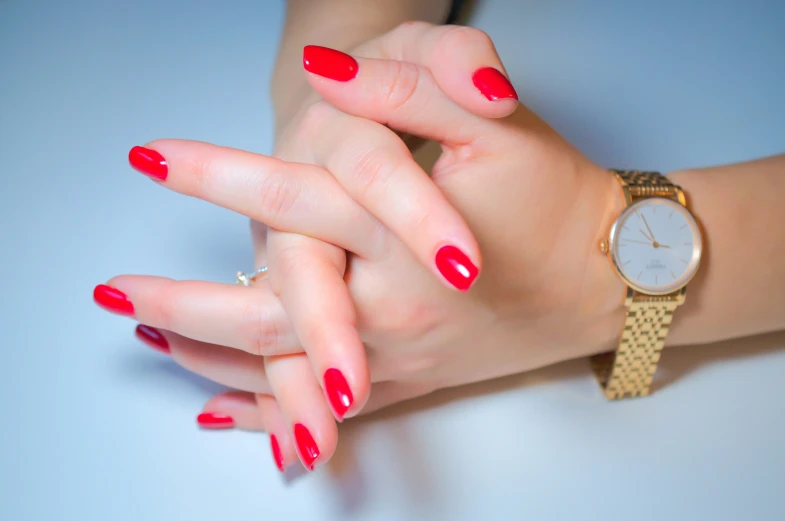 a lady with a red nail polish holding her hand with her wrist