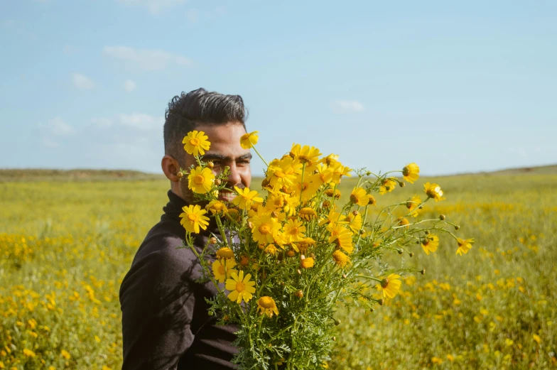 a man in black holding flowers and posing for a picture