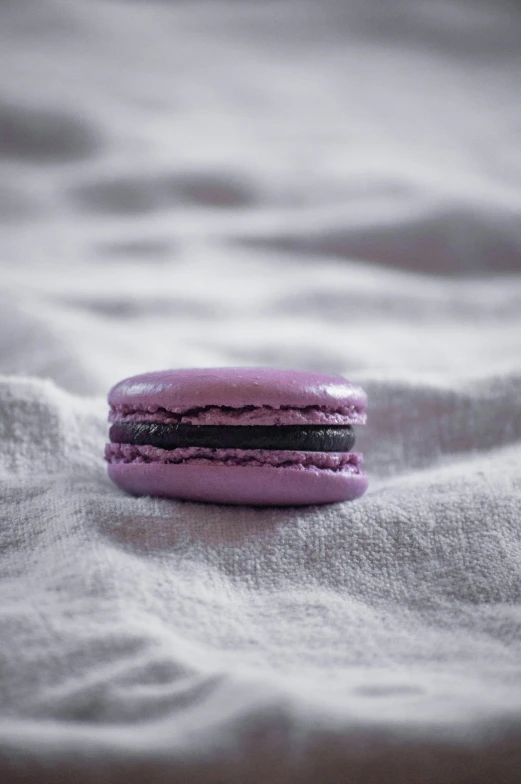 a pink colored macaron resting on top of a white blanket