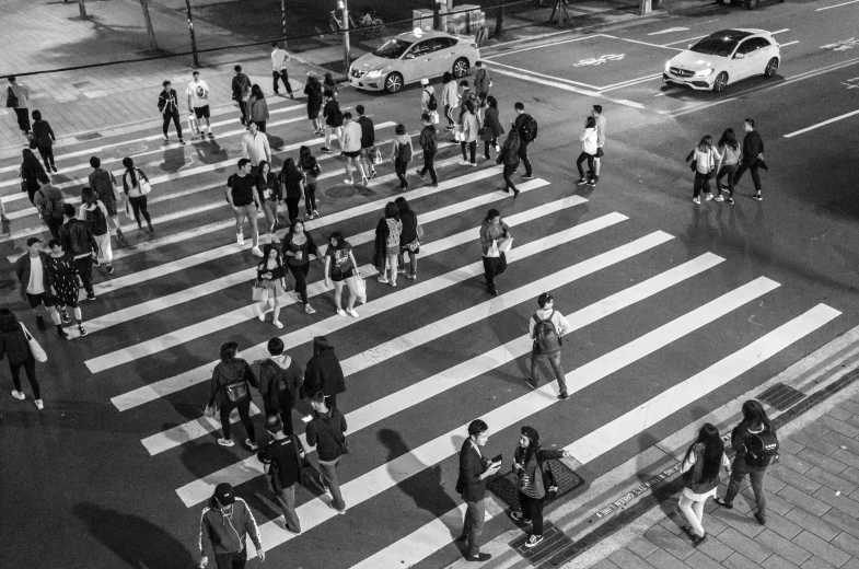 an aerial view of many people walking across a city street