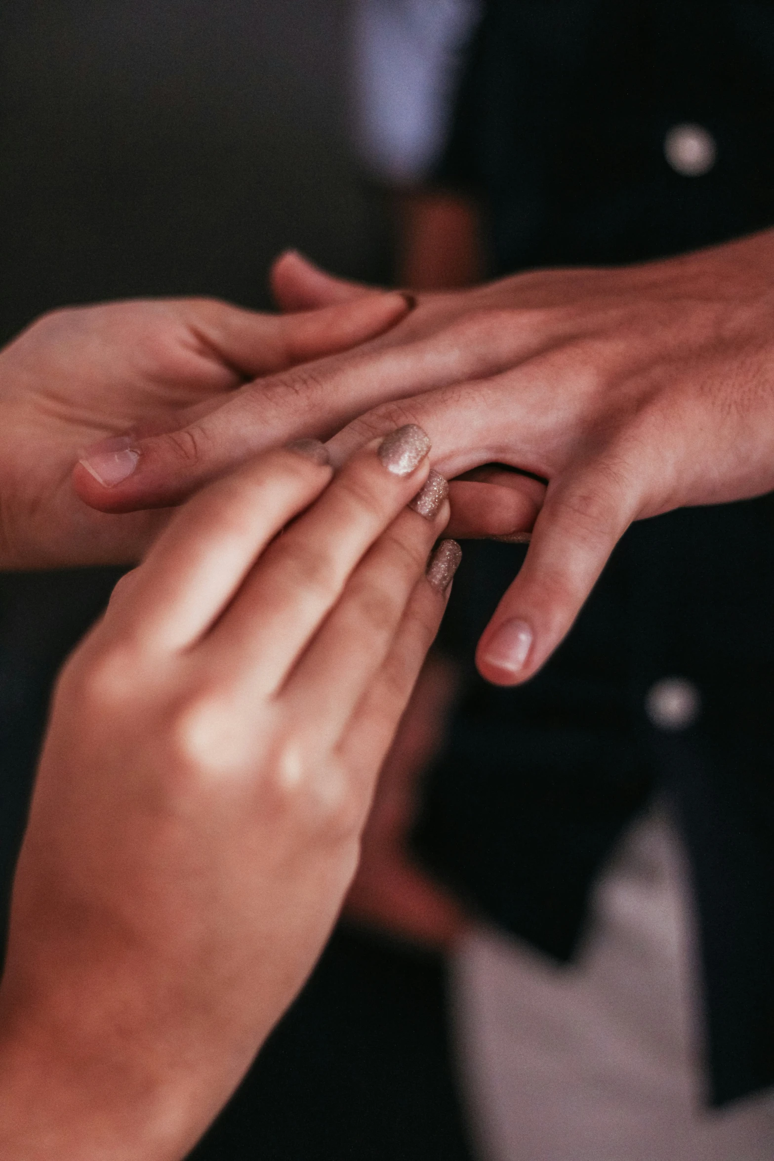 a closeup s of two hands reaching for an engagement ring