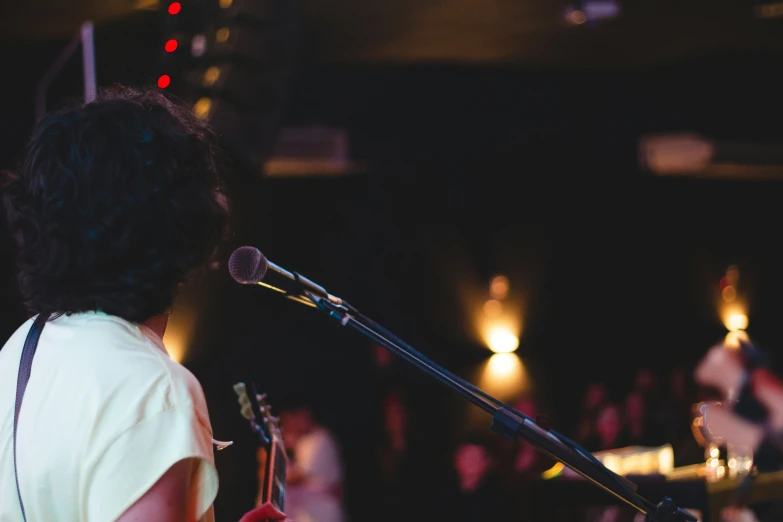 a person standing at a microphone with their hand up