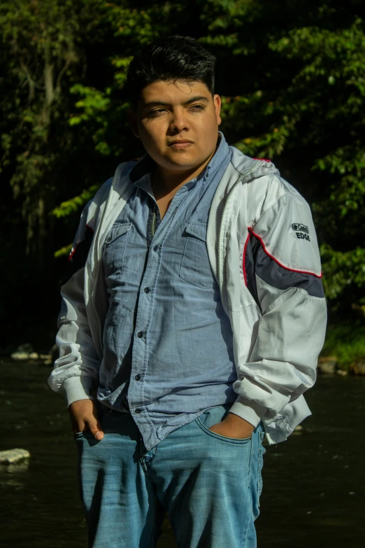 man standing by water with blue jean pants and jacket