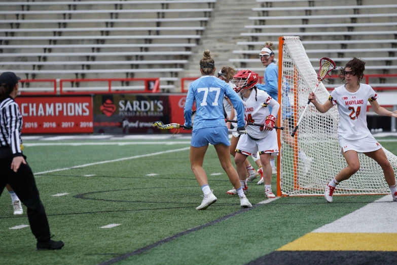 women lacrosse players playing in a game with an umpire looking on