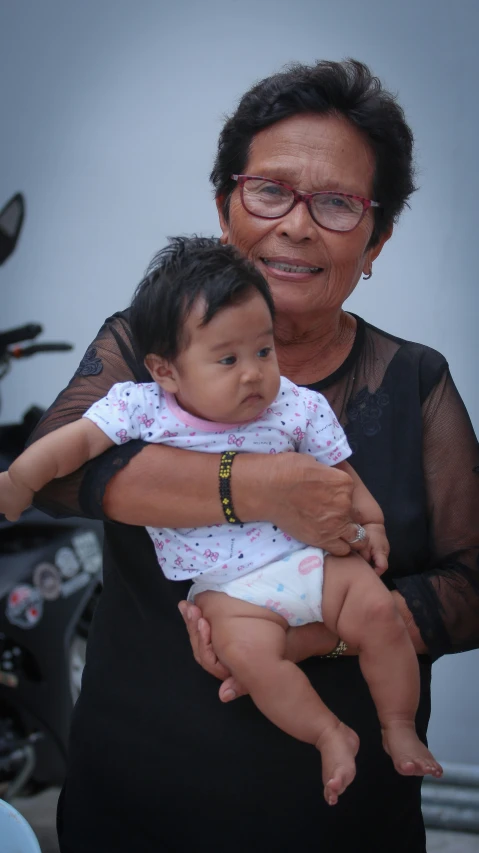 an old woman is holding a baby and smiling