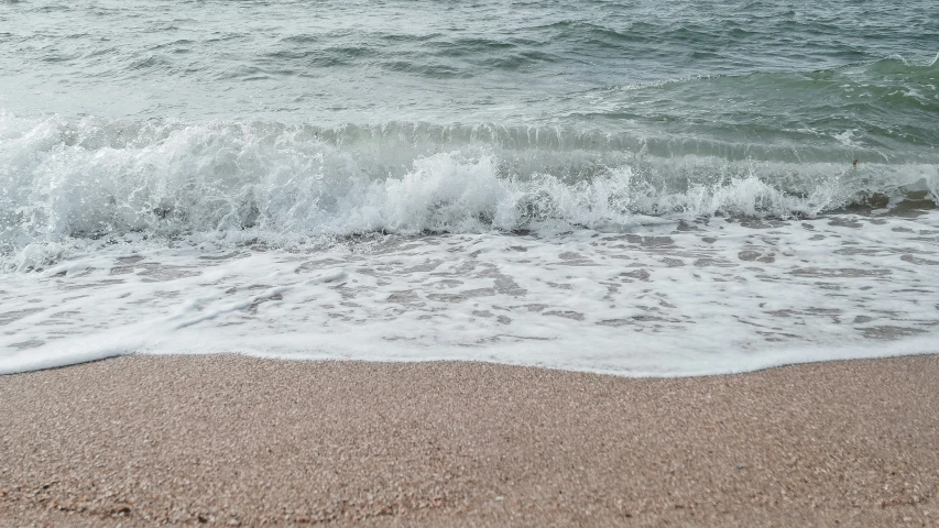 an empty sand beach with waves on the water