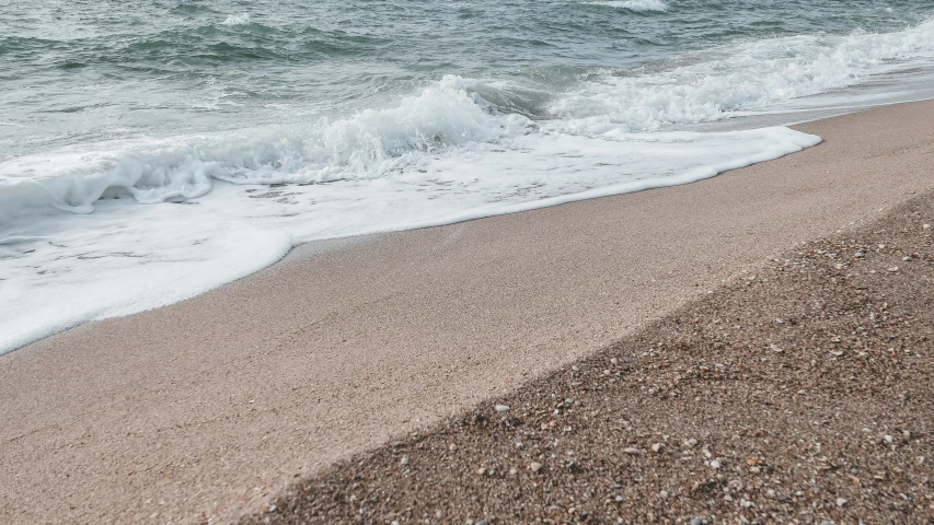 a close up of the sand on a beach next to the water