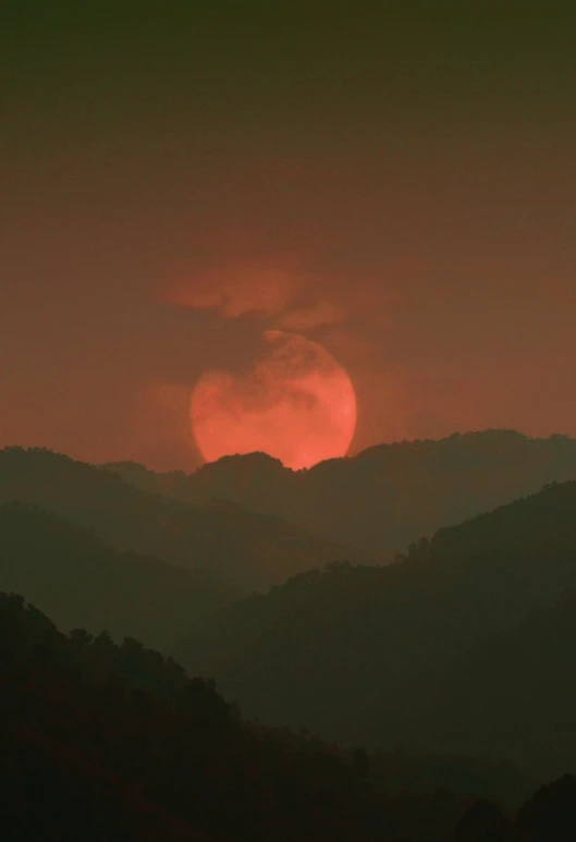 a red sky over the top of some hills