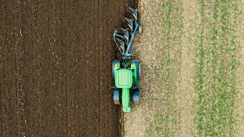 the top view of a green tractor being worked on a field