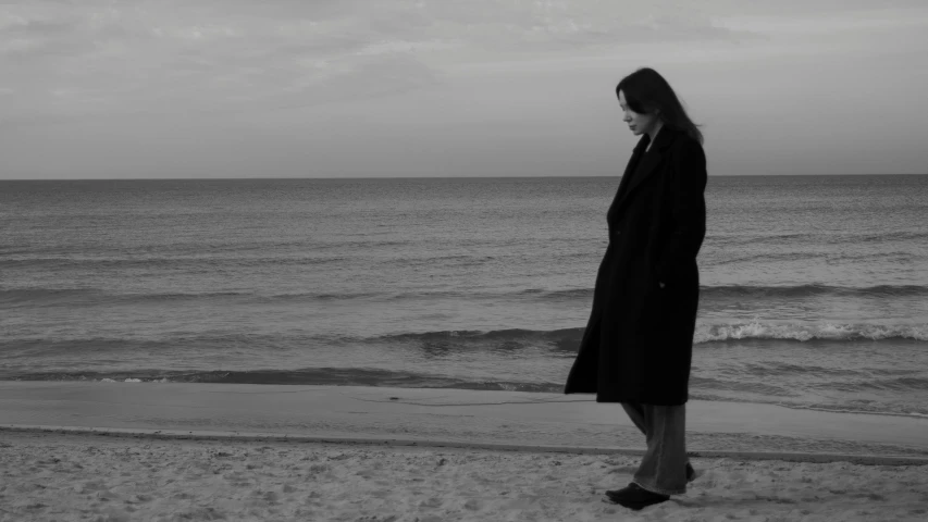 a woman standing on the beach in front of a body of water