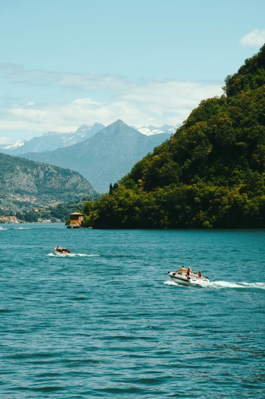 two people on skis, out on the water with some mountains in the background