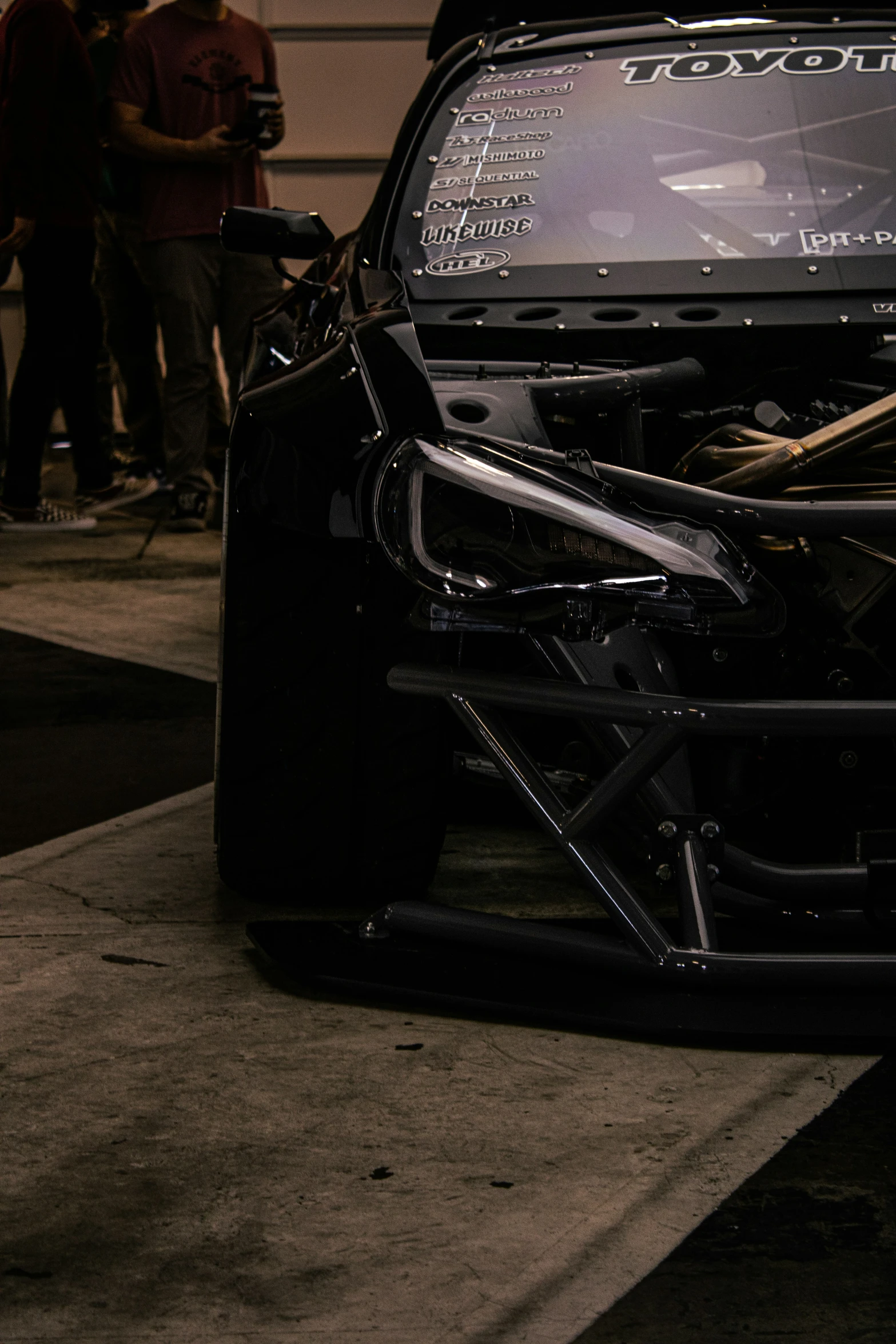 a car's engine is seen while people stand around