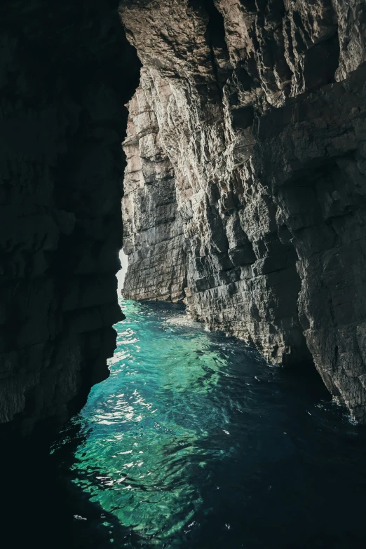 the ocean in front of a rock cliff