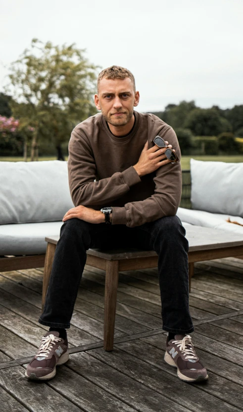 a man sitting on top of a wooden bench next to a white couch