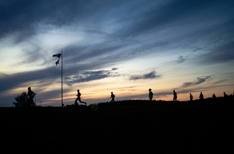 silhouettes of people walking with american flag flying in the distance