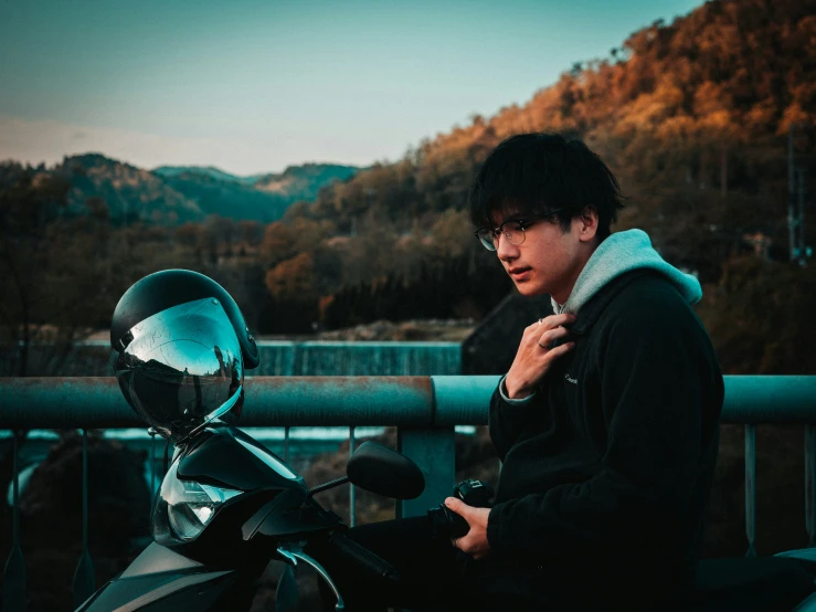 a young person sitting on a motorcycle near some mountains