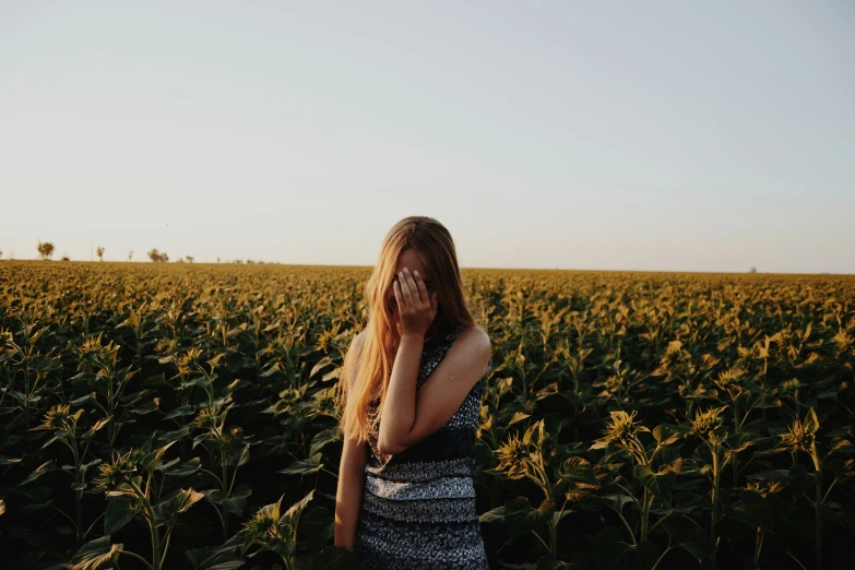 a woman stands alone in a field of sunflowers