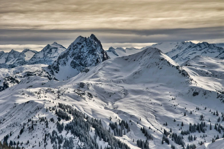 snow covered mountains under gray skies during a cloudy day