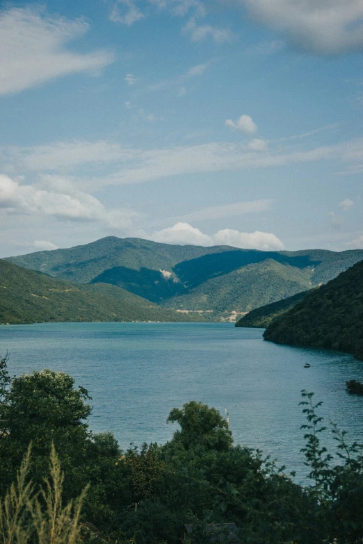 a beautiful view of blue water with lush green hills in the distance