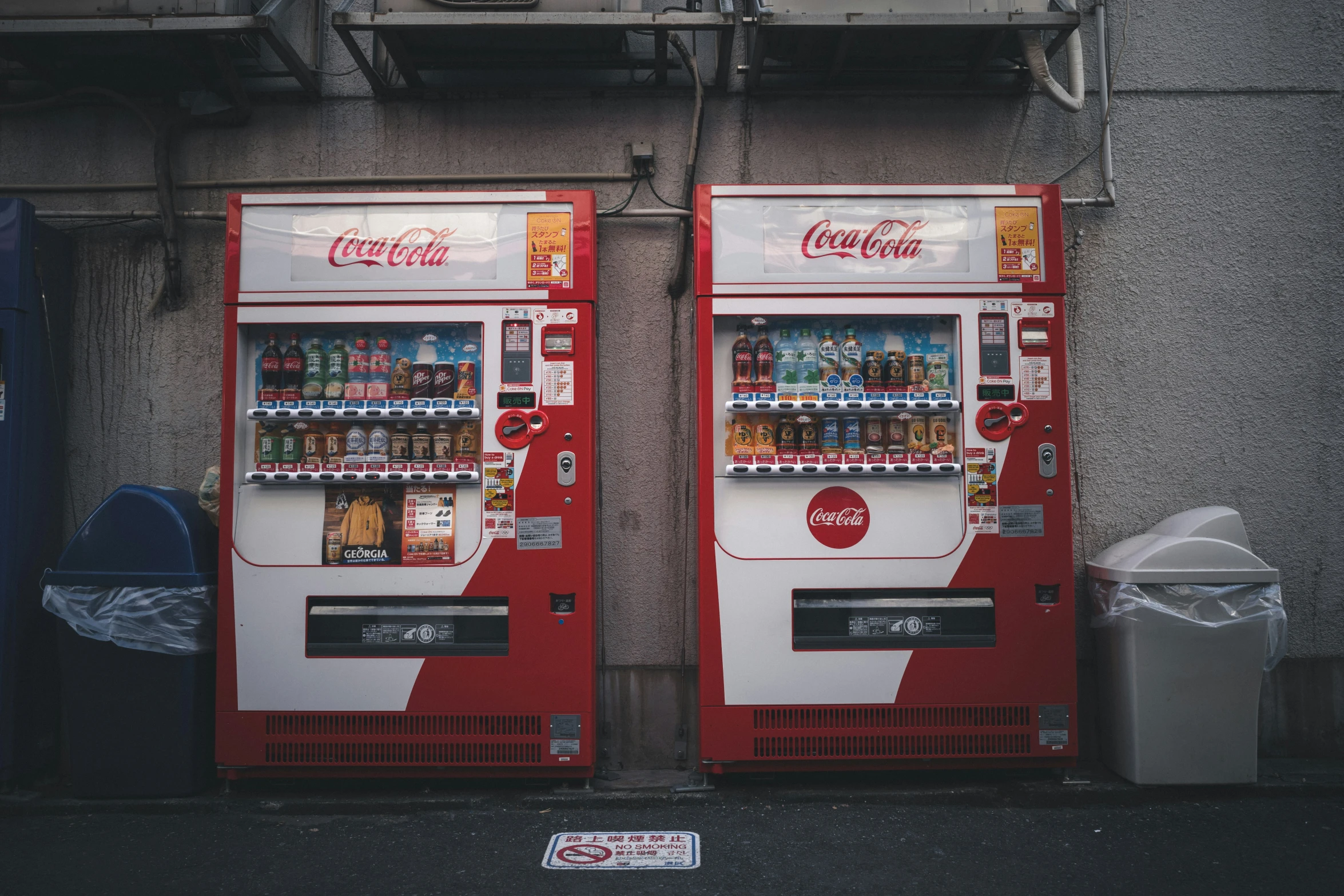 two coca - cola machines in front of an industrial building