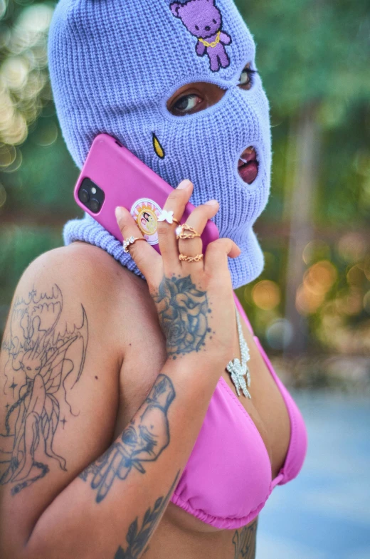 a young woman with a mask on, holding a cellphone