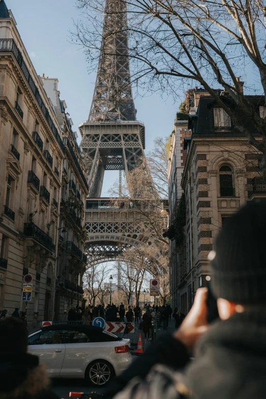 a woman taking a picture in front of the eiffel tower