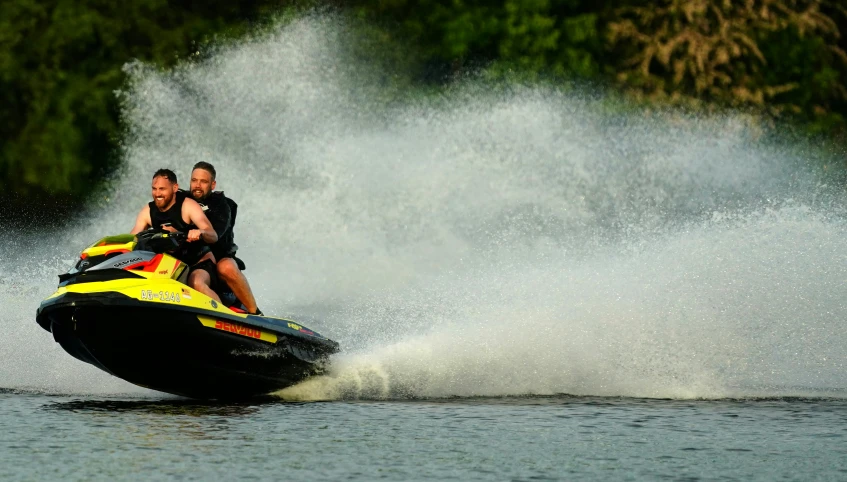 two men on a jet ski splashing through the water